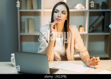 Remote-Job. Pandemie-Lockdown-Lebensstil. Arbeiten von zu Hause aus. Ablenkende, nachdenkliche, verträumte Frau, die im Büro am Arbeitsplatz sitzt Stockfoto