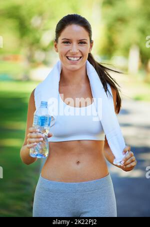 Nach H2O:00 Uhr ist es soweit. Eine Frau hält nach dem Training eine Flasche Wasser in der Hand. Stockfoto