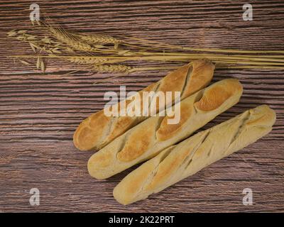 Hausgemachte brote im französischen Stil auf Holzgrund und mit Weizen- und Haferflocken-Dekoration Stockfoto