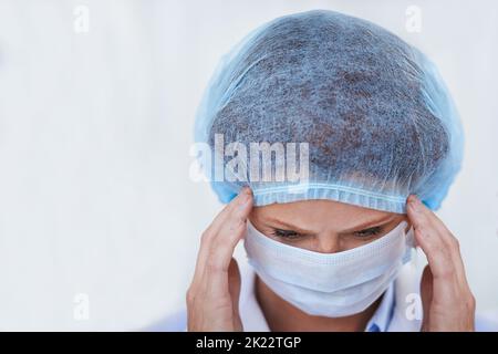 Konzentriert auf die große Operation vor uns. Eine Chirurgen trägt eine chirurgische Kappe und Maske. Stockfoto