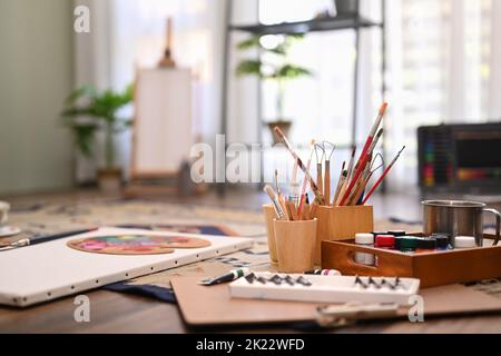Künstleratelier mit Leinwand, Pinsel, Tuben auf dem Boden. Malerraum mit Werkzeugen und Zubehör Stockfoto