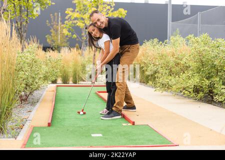 Vater und Tochter spielen gemeinsam im Park Minigolf Stockfoto