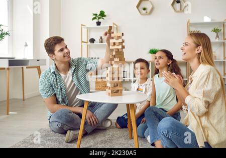 Junge Eltern und ihre beiden kleinen Kinder spielen gemeinsam Jenga. Stockfoto