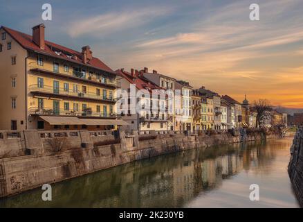 Ljubljana, Slowenien - schöner Sonnenuntergang über der Altstadt von Ljubljana mit dem Fluss Ljubljanica und traditionellen slowenischen Häusern an einem sonnigen Winternachgang Stockfoto