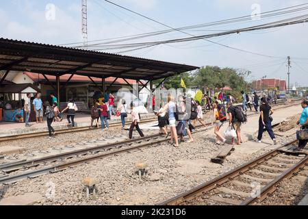 Passagiere, die die Gleise überqueren, nachdem sie am Bahnhof in Ayutthaya Thailand angekommen sind Stockfoto