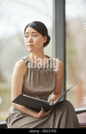 Vorbereitung auf die Vorstellung. Eine elegant gekleidete junge Frau liest sich durch einen Ordner. Stockfoto