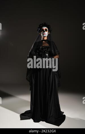 Vorderansicht der Frau in schwarzem gruseligen Kostüm und halloween Make-up auf schwarzem Hintergrund, Stockbild Stockfoto
