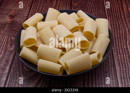 Traditionelle italienische, ungekochte Paccheri Pasta aus Gragnano auf einem Holztisch. Stockfoto
