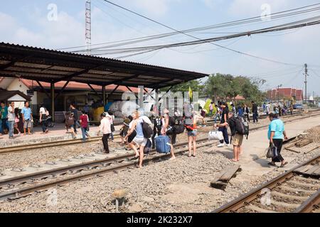 Passagiere, die die Gleise überqueren, nachdem sie am Bahnhof in Ayutthaya Thailand angekommen sind Stockfoto