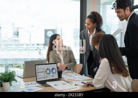 Verschiedene Geschäftsleute diskutieren den Finanzplan des Unternehmens am Sitzungstisch des Sitzungssaals. Multirassisches Team verhandelt über die Entwicklung von Projekten Stockfoto