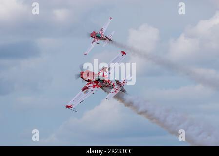 Pilot Chris Burkett fliegt ein Extra 300 Kunstflugzeug in Formation mit ferngesteuertem Modell auf der Little Gransden Air and Car Show, Bedfordshire, UK. Stockfoto