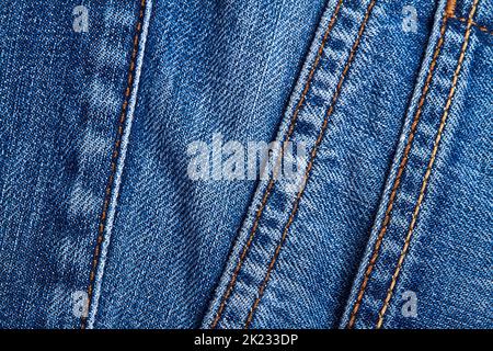 Eine blaue Denim-Jeans-Textur mit Nähten und orangefarbenen Fadenstichen Stockfoto