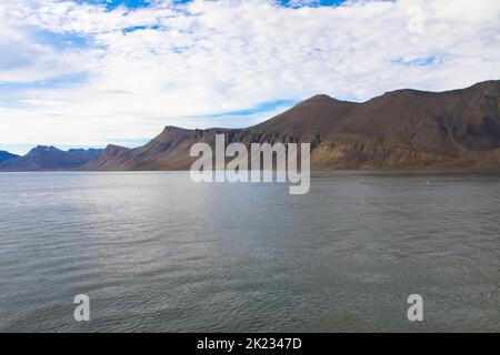 Spektakulärer Panoramablick auf die Insel Wilhelmoya mit Bergkette und blauem Himmel. Torellneset, Nordaustlandet Spitzbergen, Norwegen. Stockfoto