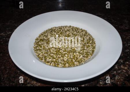 Getrockneter Split Moong Dal oder chilka Moong dal (Vigna radiata) auf einem weißen Teller in Studioaufnahmen. Uttarakhand Indien Stockfoto