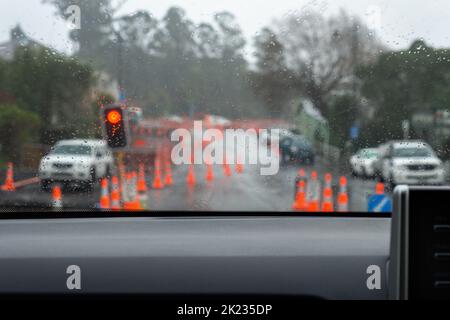 Das Fahrzeug, das an der Ampel wartet, wurde durch Straßenarbeiten angehalten. Verwackelte Verkehrskegel säumten die Straße. Dunedin, Neuseeland. Stockfoto