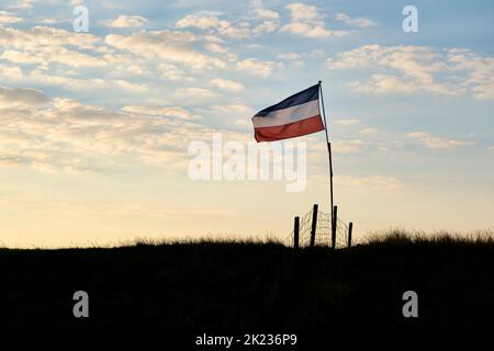 Holländische rot-weiße und blaue umgekehrte Flagge auf einem Deich bei Sonnenuntergang in den Niederlanden. Bauern in den Niederlanden protestieren. Stockfoto