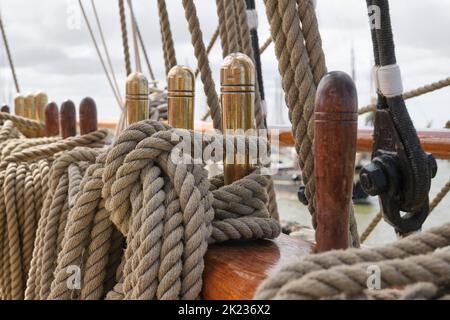 Nahaufnahme von gefesselten Seilen mit Kupfer- und Holzkeilnägeln auf einem alten traditionellen Segelschiff. Stockfoto