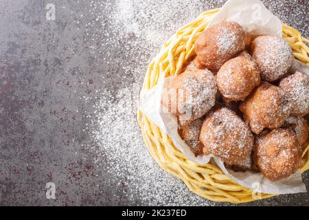 Stapel von köstlichen Oliebollen frittierten Rosinenbrötchen mit Puderzucker in den Korb auf dem Tisch zu verschließen. Horizontale Draufsicht von oben Stockfoto