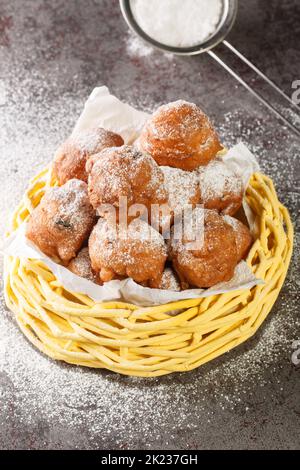 Traditioneller Oliebollen, Ölknödel oder Fritter, für den niederländischen Silvester Nahaufnahme im Korb auf dem Tisch. Vertikal Stockfoto