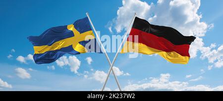 Zwei gekreuzte Flaggen Bundesrepublik Deutschland und Schweden winken im Wind bei bewölktem Himmel. Konzept von Beziehung, Dialog, Reisen zwischen zwei Countri Stockfoto