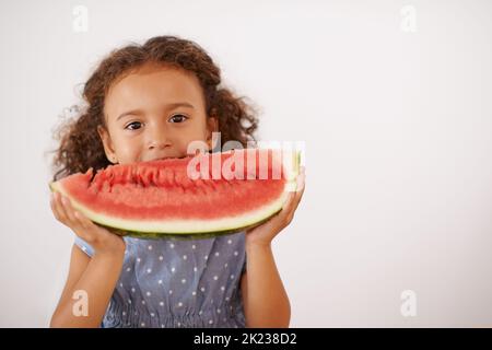 MMMM..goooooooood. Ein nettes kleines Mädchen, das Wassermelone auf Grau isoliert isst. Stockfoto