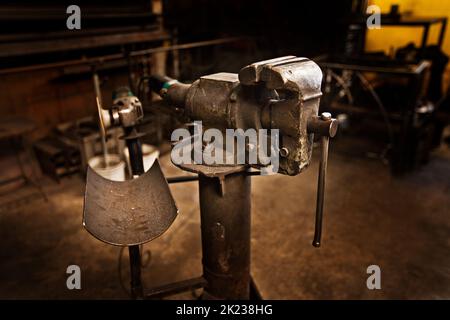 Das Handwerk einer vergangenen Ära. Ein freistehender Schraubstock mitten in einer Eisenarbeiterwerkstatt. Stockfoto