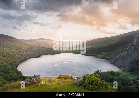 Schöner und dramatischer Sonnenuntergang am Lough Tay, genannt Guinness Lake, liegt im tiefen Tal und ist von den Wicklow Mountains, Irland, umgeben Stockfoto