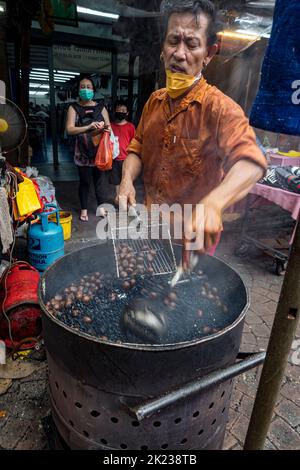 Malaysia, 10. Juli 2022 - der Mann sammelt geröstete Kastanien im Imbissstand am offenen Brunnen. Stockfoto