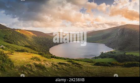 Wunderschönes Panorama mit dramatischem Sonnenuntergang am Lough Tay, genannt Guinness Lake, das sich im tiefen Tal befindet und von den Wicklow Mountains, Irland, umgeben ist Stockfoto