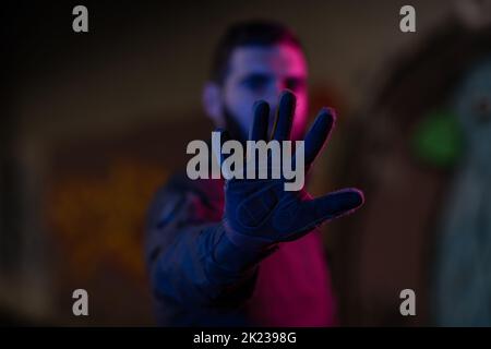 Foto eines voll ausgestatteten Soldaten in schwarzer Rüstung taktische Weste und Handschuhe stehen auf schwarzem Hintergrund Nahaufnahme Vorderansicht. Stockfoto