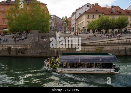 Ljubljana, Slowenien - September 3. 2022. Ein Touristenboot fährt entlang der Uferpromenade des Flusses Ljubljanici im Zentrum von Ljubljana, Slowenien Stockfoto