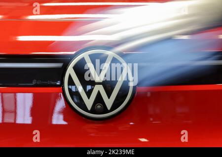 Zwickau, Deutschland. 26. April 2022. Ein Mitarbeiter wischt im Lichttunnel im Volkswagen-Werk in Zwickau das VW-Logo auf einer ID.4 ab. Neben VW-Fahrzeugen kommen im Werk auch Fahrzeuge der Marken Audi und Seat vom Band. Die Fahrzeuge basieren auf dem Modular Electric Toolkit. Volkswagen hat den rund 9.000 Mitarbeiter beschäftigende Standort zu einem reinen Elektrofahrzeugwerk für 1,2 Milliarden Euro umgebaut. Quelle: Jan Woitas/dpa/Alamy Live News Stockfoto
