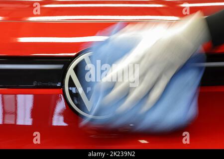 Zwickau, Deutschland. 26. April 2022. Ein Mitarbeiter wischt im Lichttunnel im Volkswagen-Werk in Zwickau das VW-Logo auf einer ID.4 ab. Neben VW-Fahrzeugen kommen im Werk auch Fahrzeuge der Marken Audi und Seat vom Band. Die Fahrzeuge basieren auf dem Modular Electric Toolkit. Volkswagen hat den rund 9.000 Mitarbeiter beschäftigende Standort zu einem reinen Elektrofahrzeugwerk für 1,2 Milliarden Euro umgebaut. Quelle: Jan Woitas/dpa/Alamy Live News Stockfoto