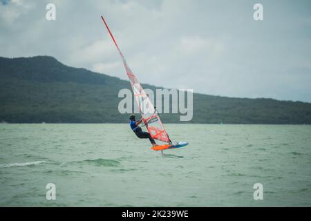 Ein Mann nimmt an einem nationalen Windsurf-Hydrofoil-Rennen beim Waterbourne Watersports Festival, Takapuna Beach, Auckland, Neuseeland, Teil. Stockfoto