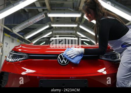 Zwickau, Deutschland. 26. April 2022. Ein Mitarbeiter wischt im Lichttunnel im Volkswagen-Werk in Zwickau das VW-Logo auf einer ID.4 ab. Neben VW-Fahrzeugen kommen im Werk auch Fahrzeuge der Marken Audi und Seat vom Band. Die Fahrzeuge basieren auf dem Modular Electric Toolkit. Volkswagen hat den rund 9.000 Mitarbeiter beschäftigende Standort zu einem reinen Elektrofahrzeugwerk für 1,2 Milliarden Euro umgebaut. Quelle: Jan Woitas/dpa/Alamy Live News Stockfoto