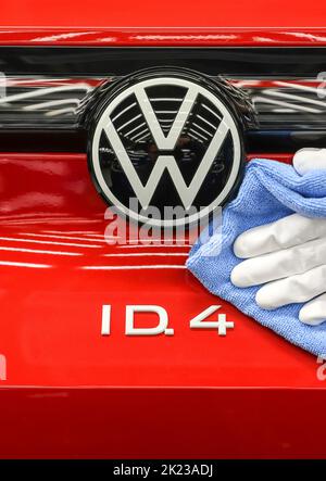 Zwickau, Deutschland. 26. April 2022. Ein Mitarbeiter wischt im Lichttunnel im Volkswagen-Werk in Zwickau das VW-Logo auf einer ID.4 ab. Neben VW-Fahrzeugen kommen im Werk auch Fahrzeuge der Marken Audi und Seat vom Band. Die Fahrzeuge basieren auf dem Modular Electric Toolkit. Volkswagen hat den rund 9.000 Mitarbeiter beschäftigende Standort zu einem reinen Elektrofahrzeugwerk für 1,2 Milliarden Euro umgebaut. Quelle: Jan Woitas/dpa/Alamy Live News Stockfoto