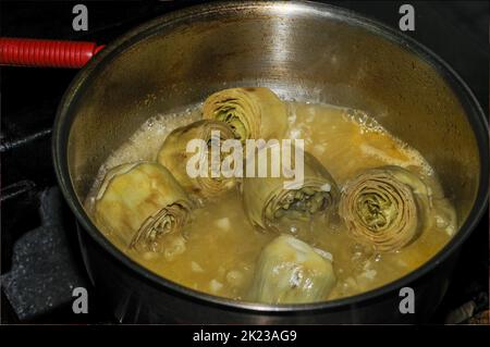 Artischocken kochen in einem Metalltopf Stockfoto