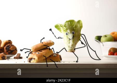 Gesundes Essen und ungesundes Lebensmittelkonzept mit supersalatgewinnenden industriellen Backwaren auf Küchenbank mit isoliertem Hintergrund. Vorderansicht. Stockfoto