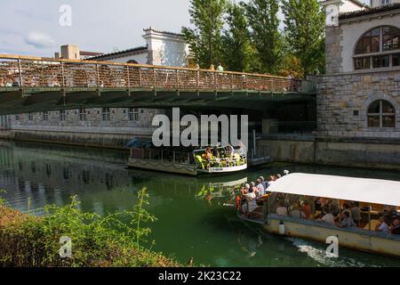 Ljubljana, Slowenien - September 3. 2022. Unter der Metzgerbrücke fahren Touristenboote über den Fluss Ljubljanici im Zentrum von Ljubljana, Slowenien. Stockfoto