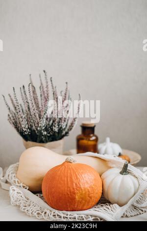 Stillleben im Herbst mit Kürbissen und goldenen Blättern auf einer hölzernen Oberfläche. Herbst Kürbis Danksagung Hintergrund mit Zero Waste wiederverwendbaren Beutel mit Stockfoto