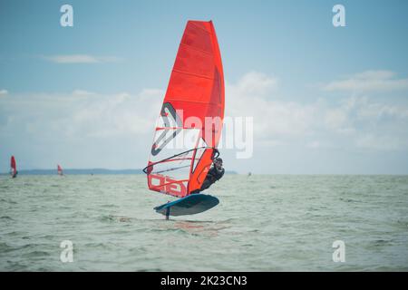 Ein Mann nimmt an einem nationalen Windsurf-Hydrofoil-Rennen beim Waterbourne Watersports Festival, Takapuna Beach, Auckland, Neuseeland, Teil. Stockfoto