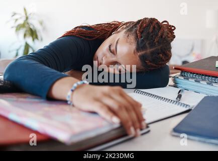 Müde Studentin, die an ihrem Schreibtisch schläft, während sie für Universitäts- oder Hochschulprüfungen und Prüfungen studiert. Burnout junge Frau liegt auf dem Schreibtisch, Müdigkeit oder Schlaf während Stockfoto