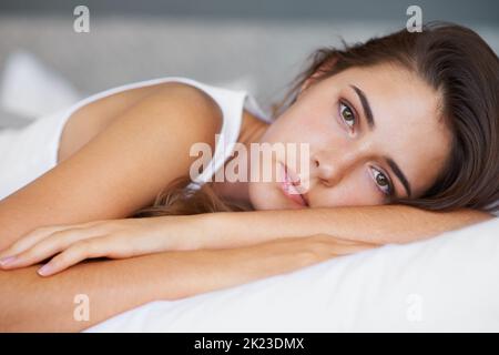 Heute habe ich viel im Kopf... Eine schöne junge Frau, die traurig aussieht, als sie auf ihrem Bett liegt. Stockfoto