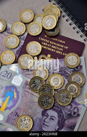 Britische Pfund Sterling, 20 Pfund Banknoten und 1 Pfund Münzen abgebildet. Britische und europäische britische Pässe und türkische Lire. Kann für Reisen, Inflation verwendet werden. Stockfoto