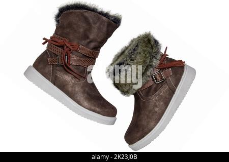 Kinder Winterstiefel. Nahaufnahme eines Paares eleganter Winterstiefel aus braunem Wildleder und gefüttert mit Fell. Mädchen Winterschuh Mode neue Trends isoliert Stockfoto