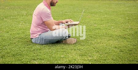 Zugeschnittenes Geschäftsmann mit Laptop zum Bloggen auf grünem Gras, Kopierplatz, Netzwerkadministrator Stockfoto