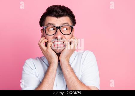 Nahaufnahme Foto von jungen attraktiven schönen Bart Gesicht nervös Mann tragen weißes Polo T-Shirt Biss Nägel suchen leeren Raum ad isoliert auf rosa Farbe Stockfoto