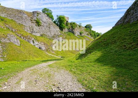 Breiter Fußweg durch Cave Dale biegt zwischen vertikalen Kalksteinwänden nach rechts ab. Stockfoto