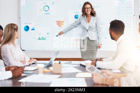 Business Manager, der eine Unternehmenspräsentation vor einem Team im Konferenzraum des Unternehmens vorführt. Geschäftstreffen mit Diagrammen, Diagrammen und Datendokumenten für Stockfoto