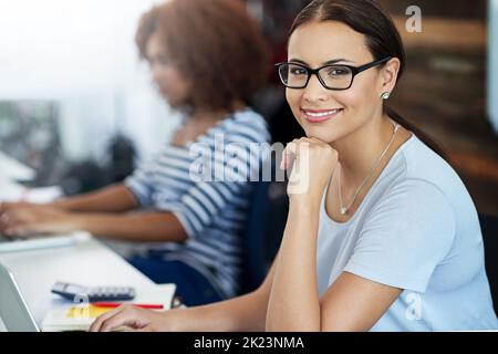 Ich habe alle meine Termine eingehalten. Das verkürzte Porträt einer attraktiven jungen Geschäftsfrau, die im Büro mit der Hand auf dem Kinn sitzt. Stockfoto